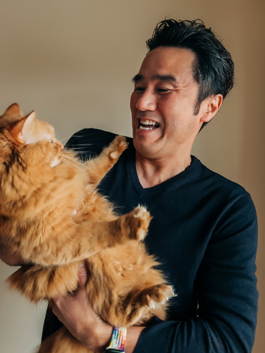 ภาพถ่าย Tetsu กำลังยิ้ม อุ้มแมว และมองไปที่แมว