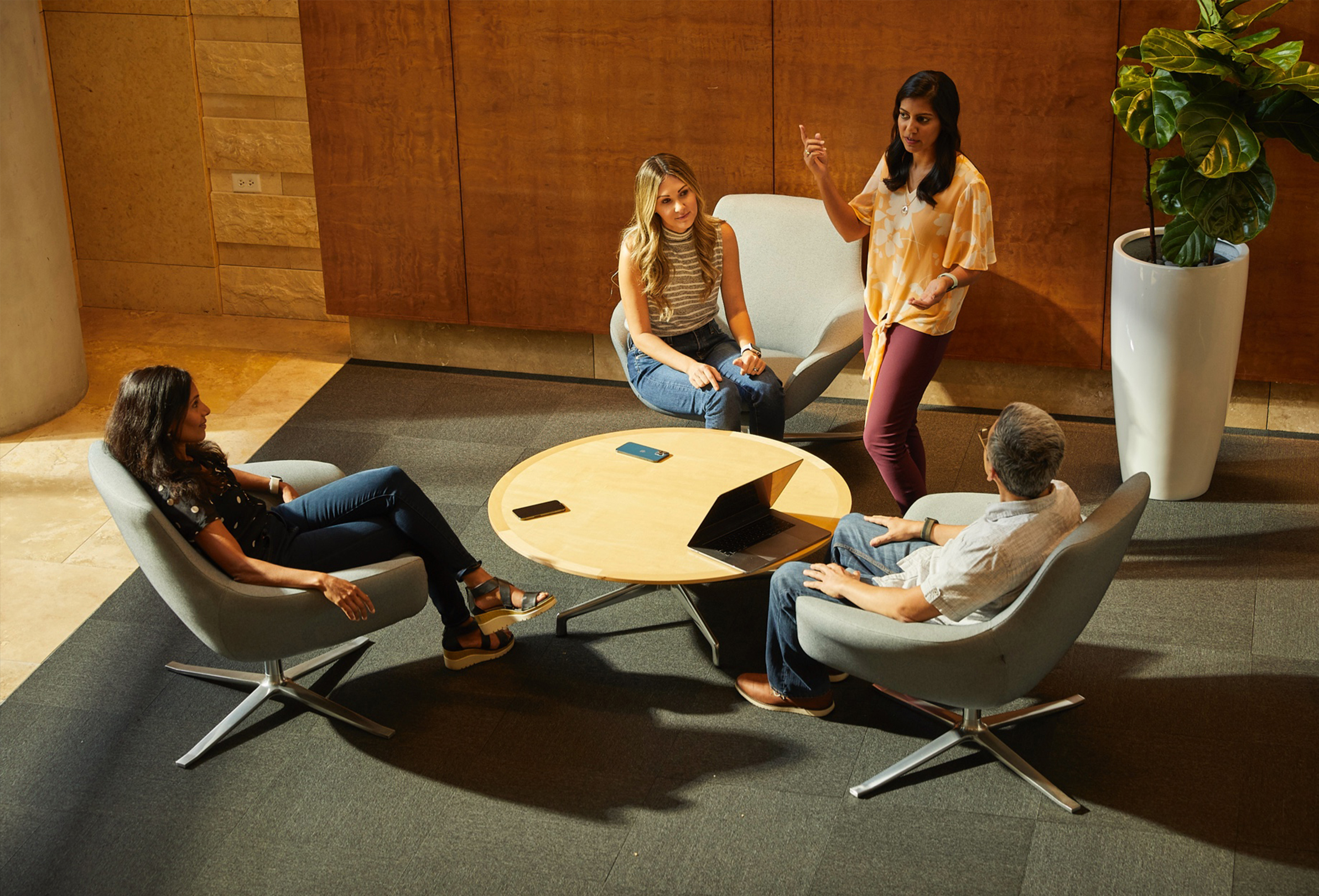 Fyra Apple-medarbetare sitter och pratar i ett trevligt rum.
