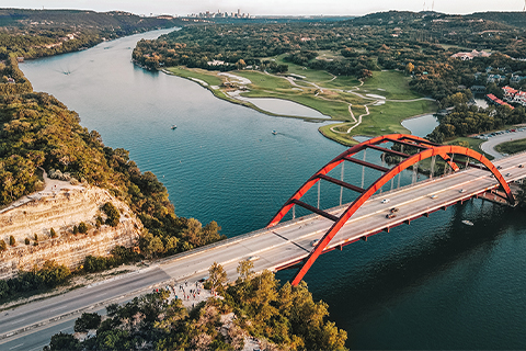 Luftfoto af en flod og en bro i Austin, Texas, med byen i baggrunden.