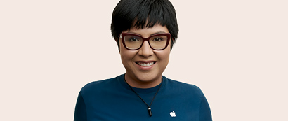 短发 Apple 零售员工戴着眼镜，面朝镜头微笑。