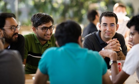  Um grupo de estagiários Apple a conversar à mesa de um Caffè Macs.